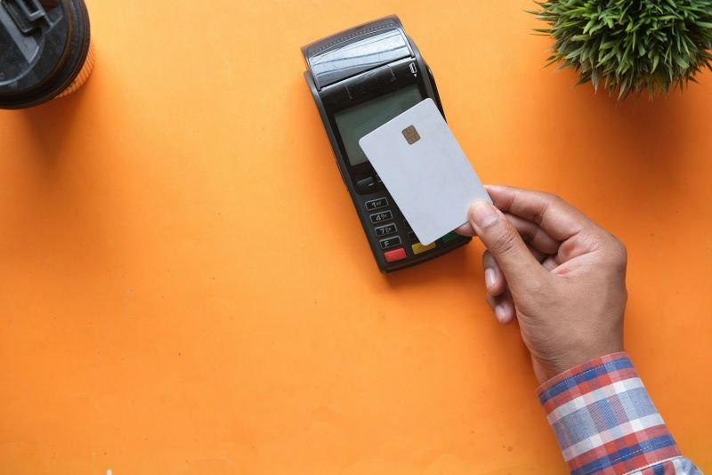 A hand holding a card to a payment terminal for a contactless purchase