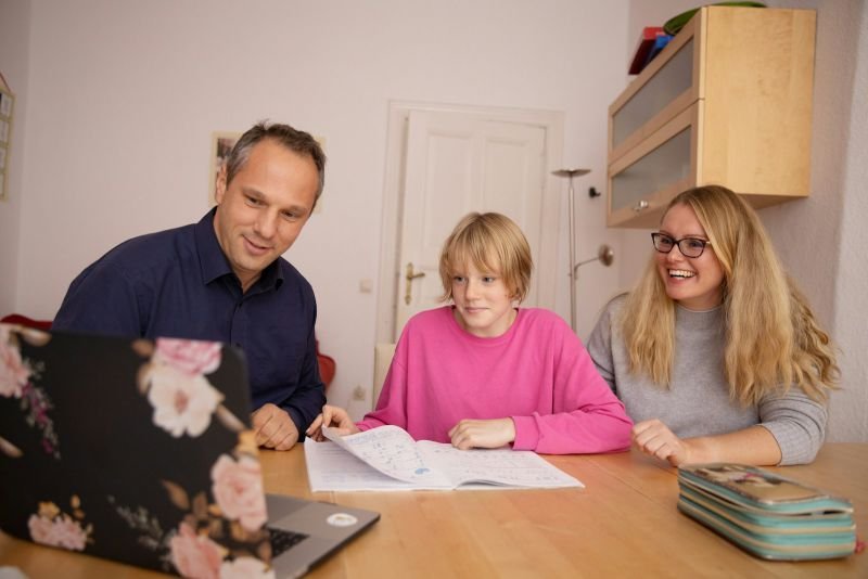 A father, mother and their child going through household papers at the kitchen table