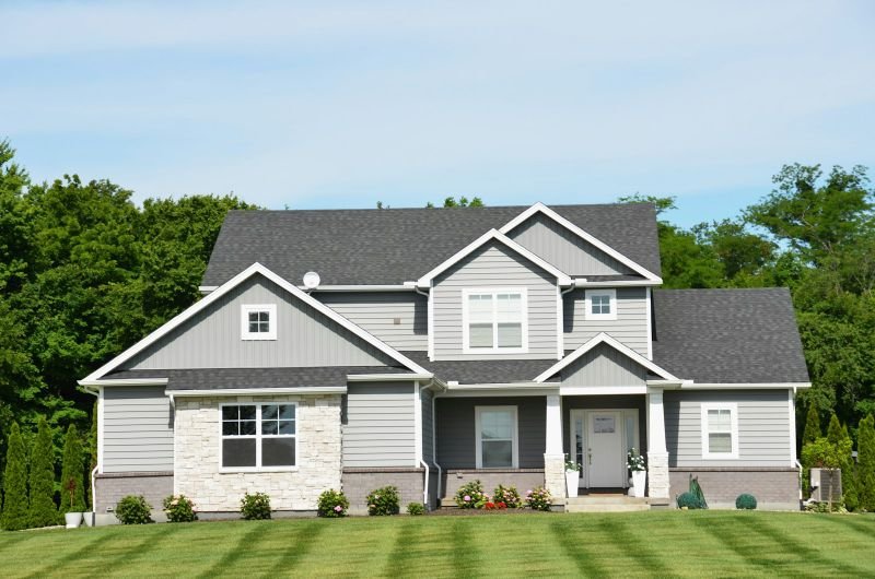A two-story family home with a neatly kept lawn on a sunny day