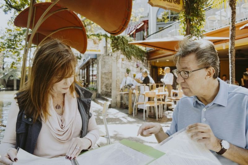 A mature couple reviewing paperwork together at an outdoor cafe table