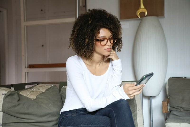 A woman reading a message on her phone with a thoughtful expression